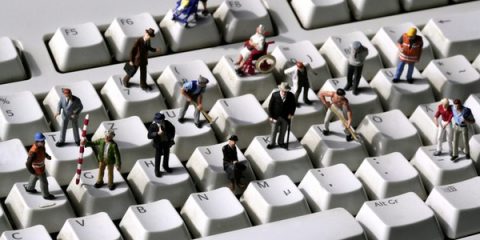 Immagine di alcuni lavoratori in miniatura su una tastiera Qwerty.