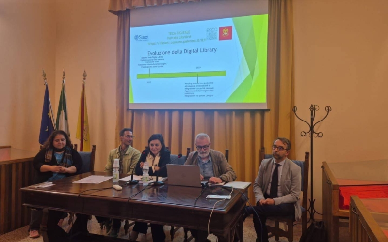 Immagine degli oratori presenti al convegno Cantieri culturali per i beni digitali. Alle spalle, gli oratori hanno un videoproiettore con un power point dal quale si evince che si parla di Evoluzione della Digital Library del Comune di Palermo.