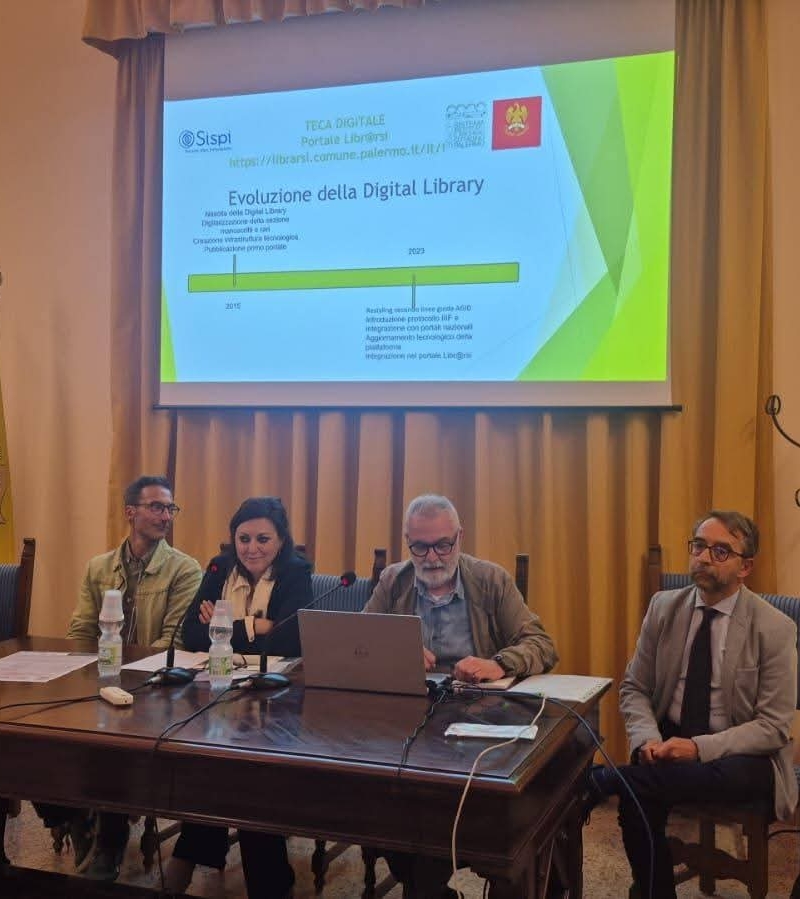 Immagine degli oratori presenti al convegno Cantieri culturali per i beni digitali. Alle spalle, gli oratori hanno un videoproiettore con un power point dal quale si evince che si parla di Evoluzione della Digital Library del Comune di Palermo.