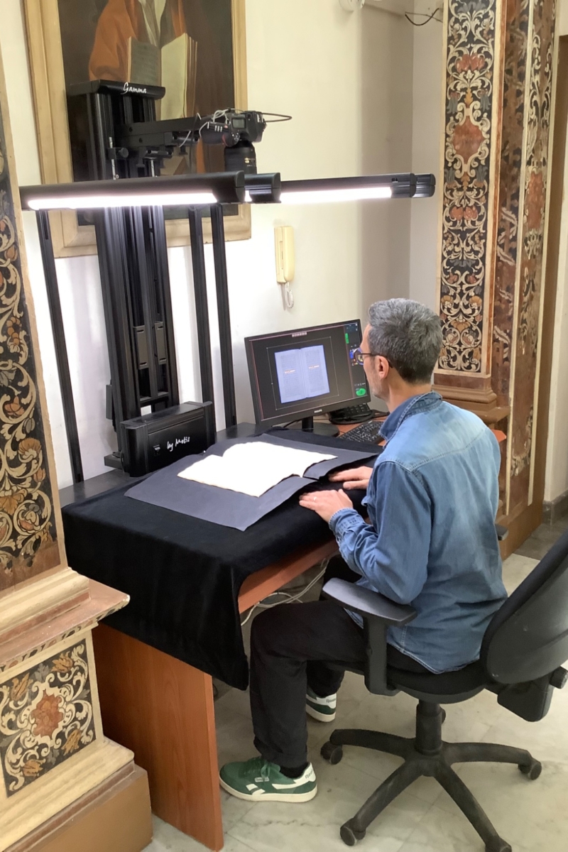 Operatore che usa uno strumento che cattura l'immagine di un testo antico per il progetto Teca Digitale.